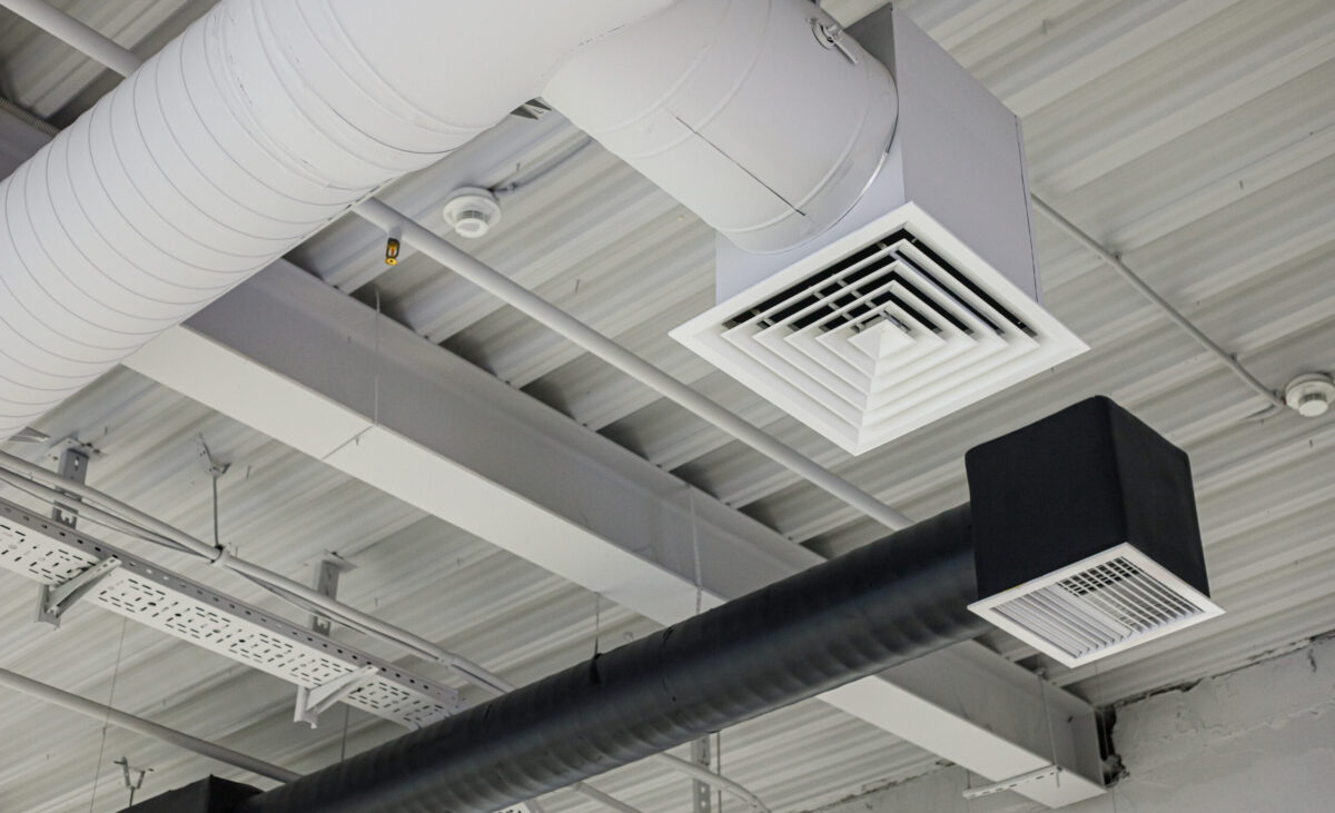 Two ventilation duct systems with grilles suspended under ceiling in commercial building. Supply and exhaust